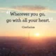 An inspirational quote by Confucius reading 'Wherever you go, go with all your heart.' in dark serif text over a sunrise view of the Paris skyline featuring the Eiffel Tower. A famous philosophical quote by Confucius encouraging passion, wholehearted commitment, and dedication in every endeavor and journey in life